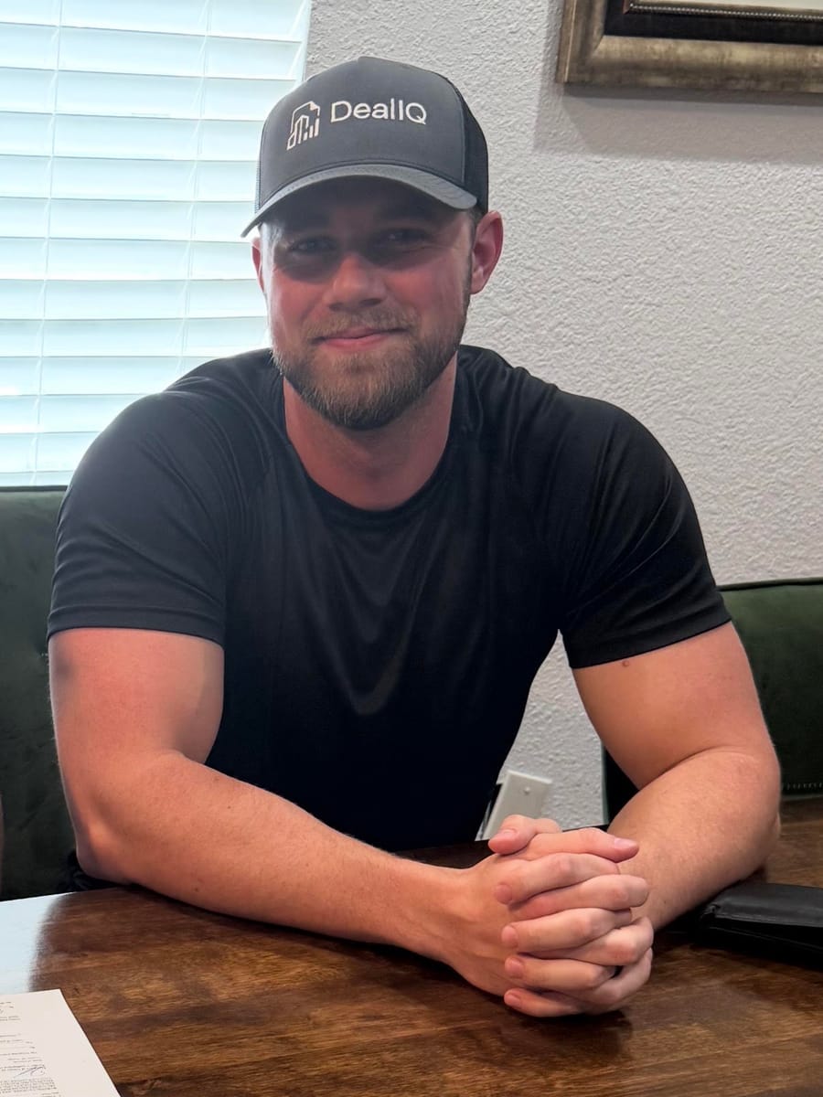 Zach Jackovich, founder of Deal IQ, in a Deal IQ hat at a closing table